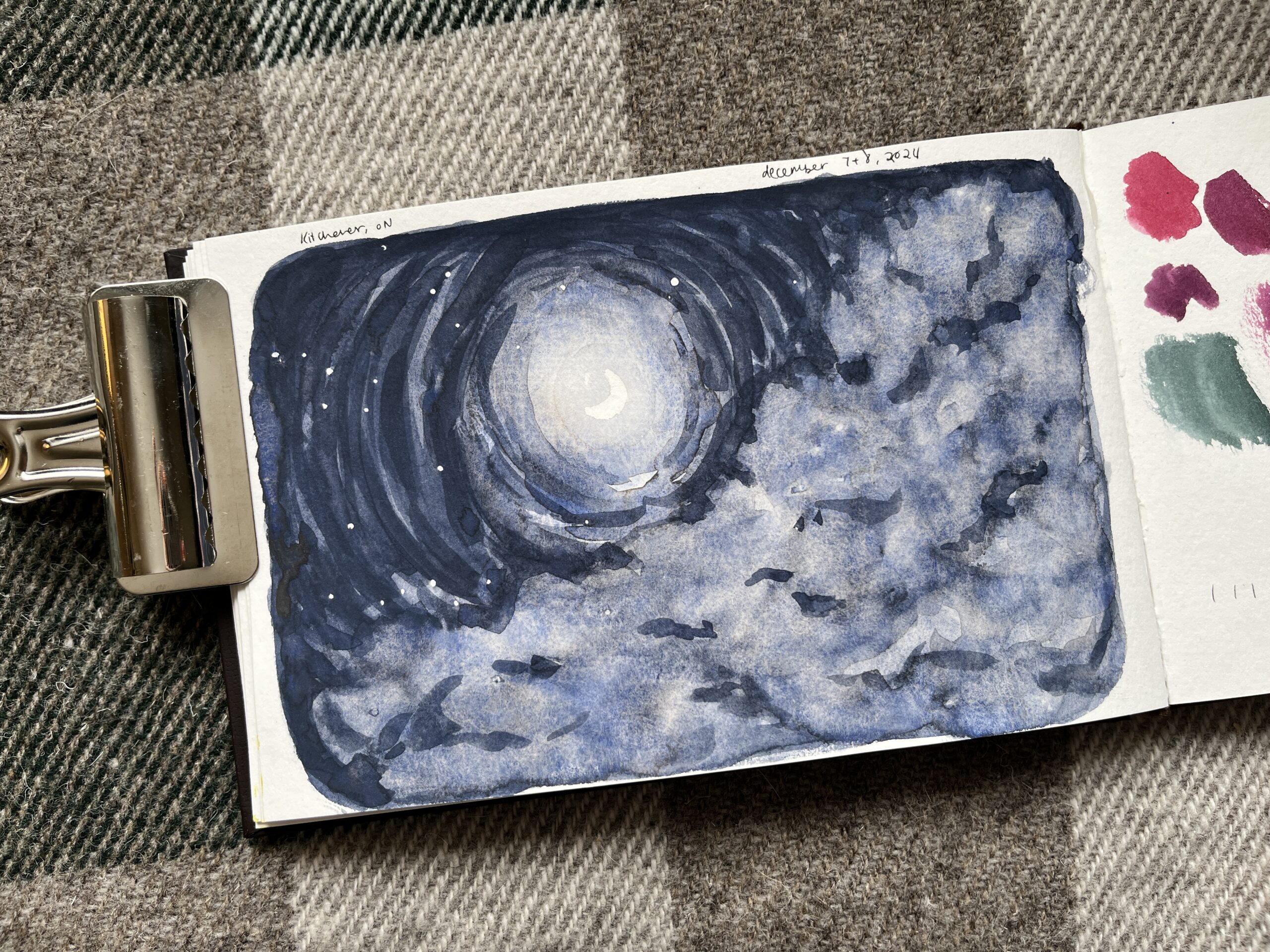 A sketchbook page, with a small crescent moon in the center. The moon appears in the negative space of a dark grey-blue sky. There is a hazy cloud covering the right side of the page.