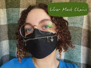 Nikki wearing a silver mask chain on a black N95 mask. There is a rectangle in the top right corner with black text that reads "Silver Mask Chains"