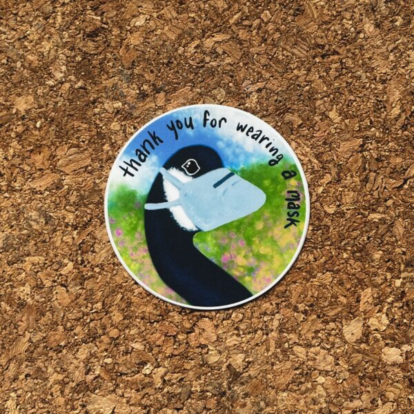Nikki's "Thank You For Wearing a Mask" sticker displayed on a cork background.