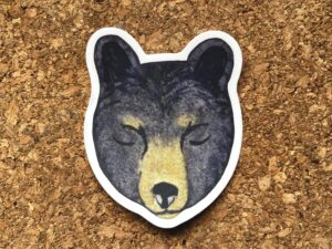 Nikki's "Winter Solstice Bear" sticker displayed on a cork background.