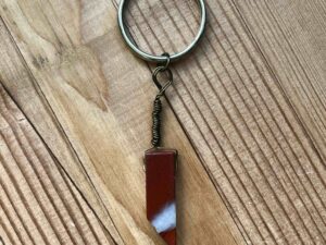 One of Nikki's keychain designs. A rectangular prism shaped red jasper crystal is wrapped with wire and attached to a silver split ring (keychain ring).
