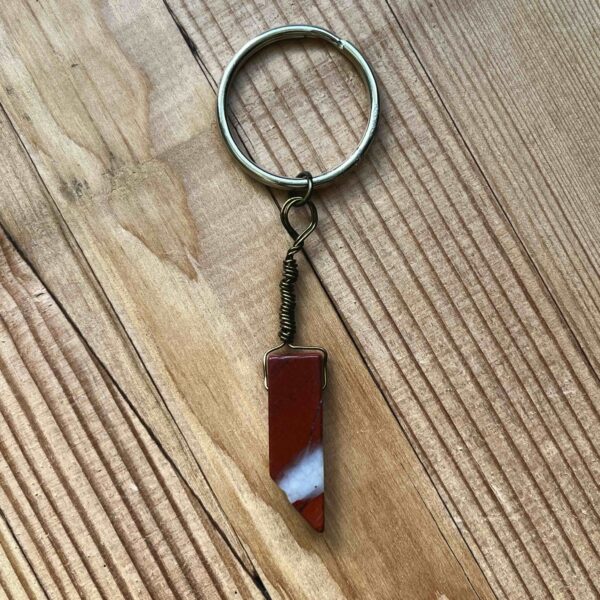 One of Nikki's keychain designs. A rectangular prism shaped red jasper crystal is wrapped with wire and attached to a silver split ring (keychain ring).