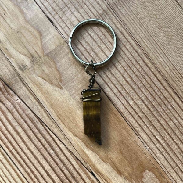 One of Nikki's keychain designs. A rectangular prism shaped tiger's eye crystal is wrapped with wire and attached to a silver split ring (keychain ring).