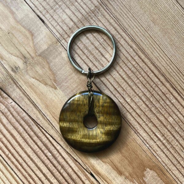 One of Nikki's keychain designs. A flat, round tiger's eye crystal is wrapped with wire and attached to a silver split ring (keychain ring).